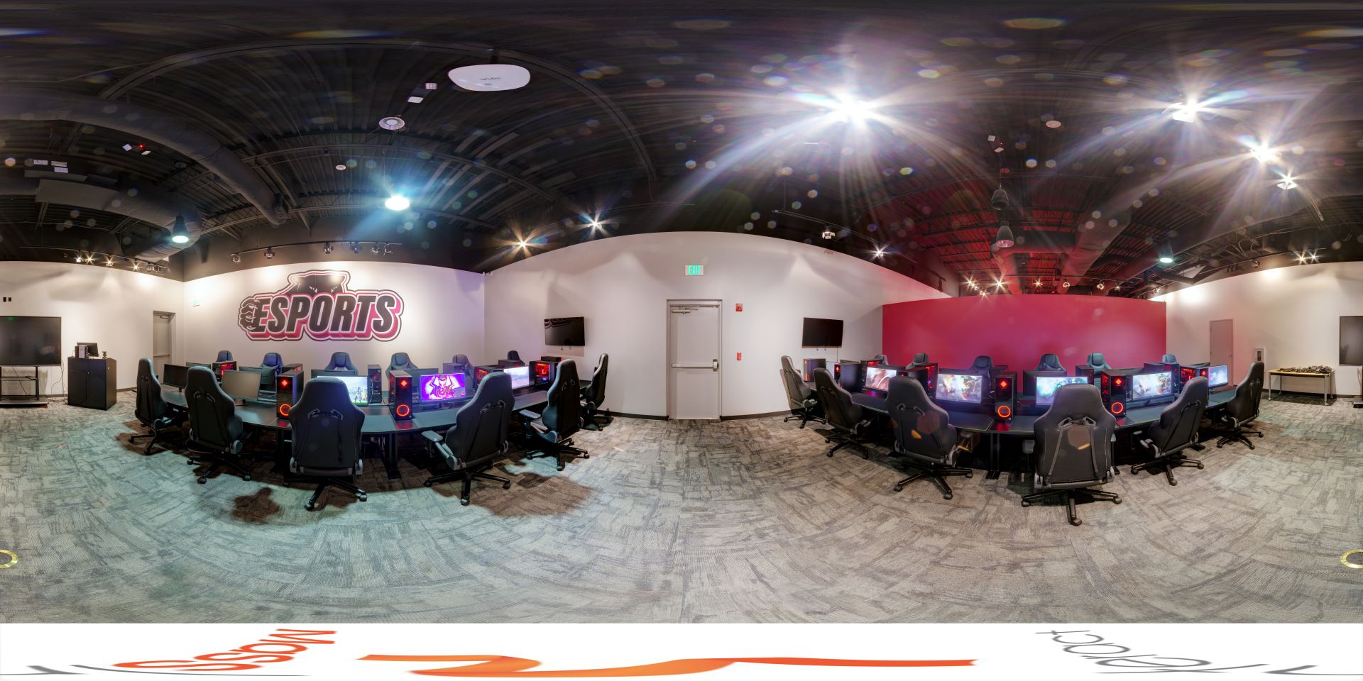 Panoramic view of the Florida Tech Esports center gaming area, featuring multiple high-performance gaming stations and seating, with esports branding on the wall